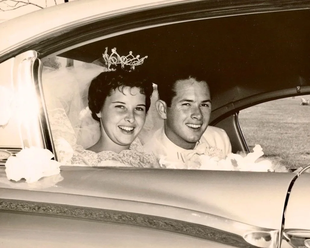 1961 Bride and groom in the backseat of car after wedding ceremony.