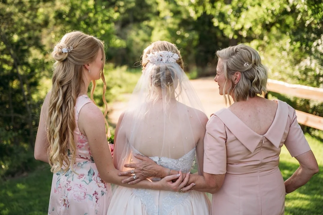 Twin sisters and mom embracing from behind waering custom bridal accessories repurposed from mom's vintage bridal headpiece.