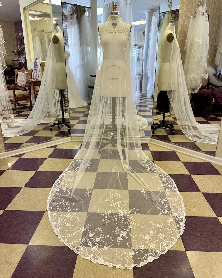 Restored vintage Brussels lace wedding veil draped over a dress form.