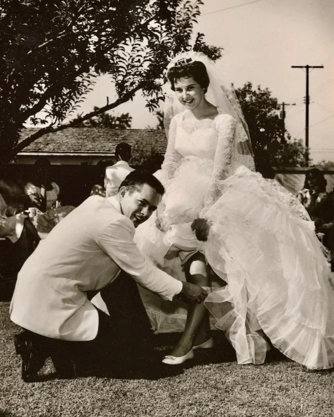 Groom removing wedding garter from leg of bride in a backyard wedding in California in 1961.