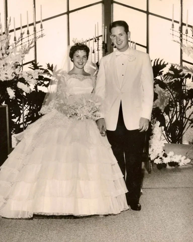Groom in white dinner jacket and bride wearing Alfred Angelo gown with 1960 wedding in chapel.