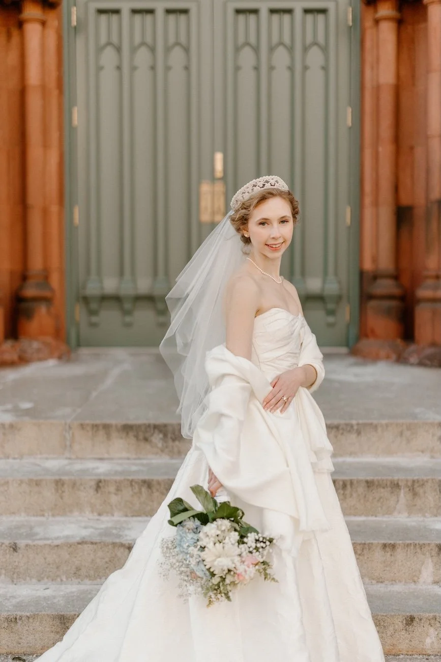 Bride in Maggie Sottero wedding gown wearing her granny's vintage headpiece on church steps.