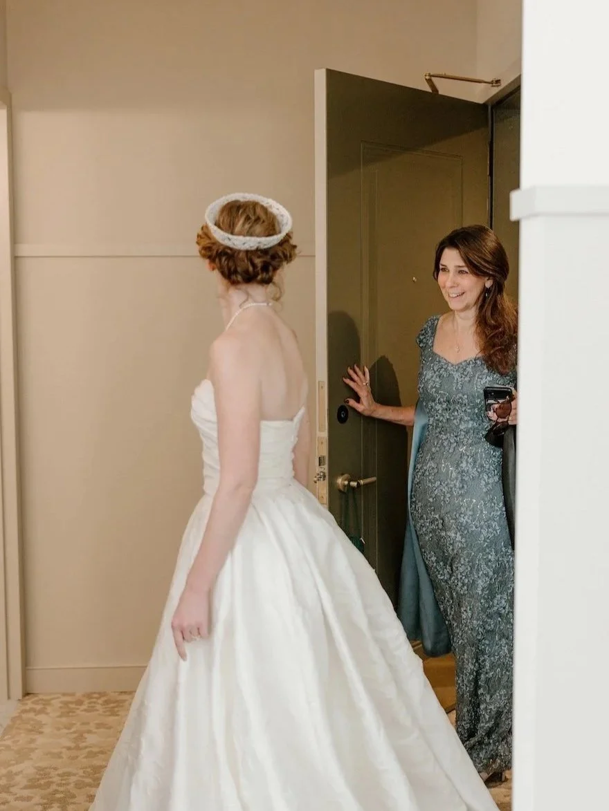 Mother of the bride in doorway seeing her daughter in her wedding gown and vintage family bridal crown.