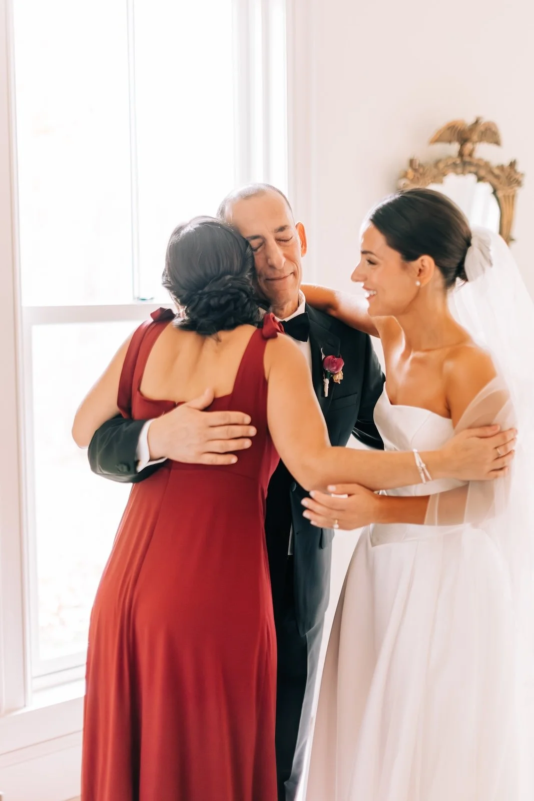 Dad hugging his two daughters with extreme emotion on her wedding day during a first look.