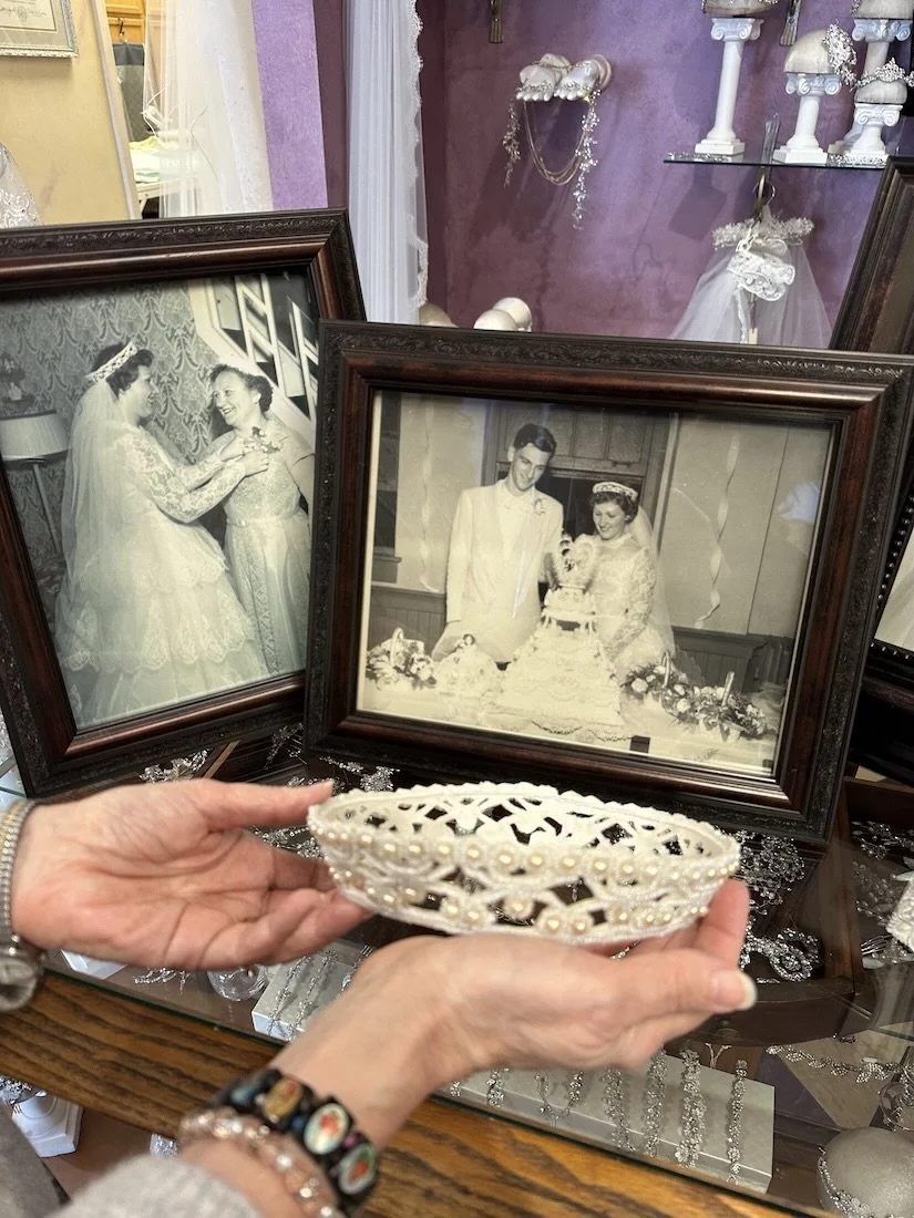 Mother of the bride holding restored beaded wedding crown with vintage wedding photos in the background.