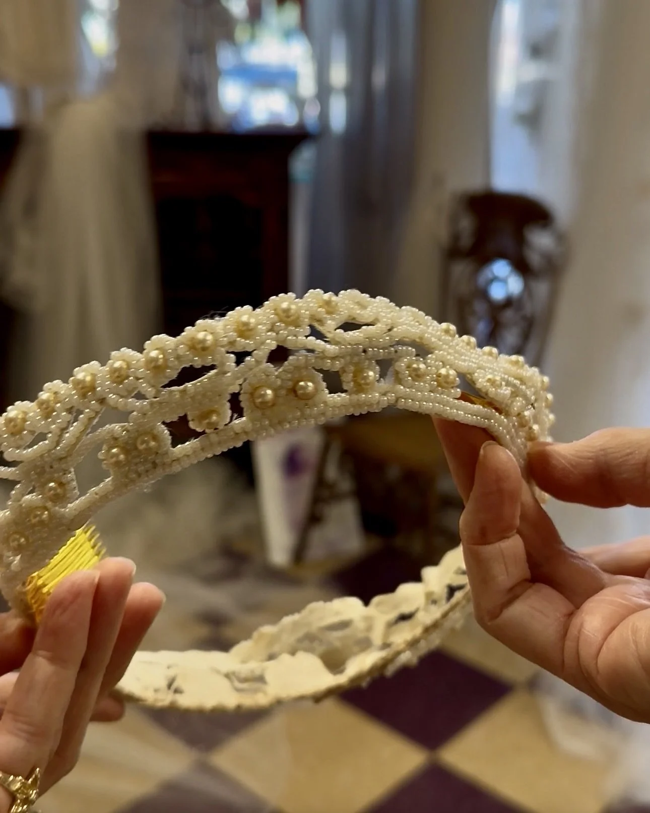 Wedding restoration expert holding a vintage crown made of seed beads and pearls in dire need of repair and restoration.