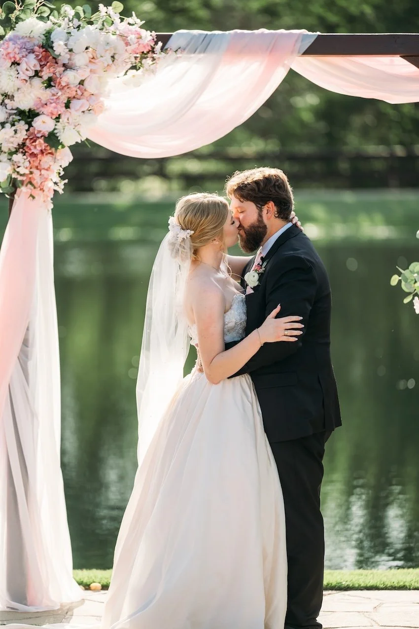 Bride and groom kissing at lakeside ceremony at Peach Creek Ranch.