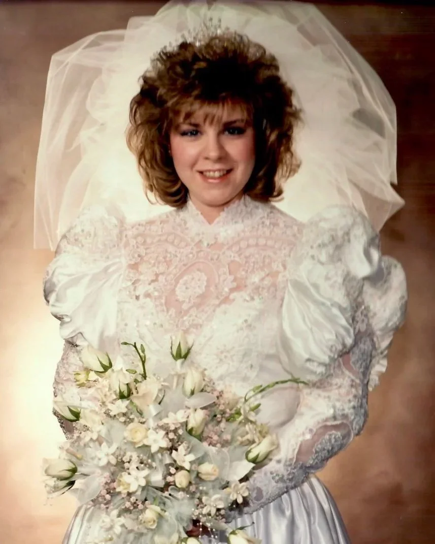 Bride wearing 1991 bridal gown with pouffy sleeves and her mother's 60s crystal tiara, holding a bouquet.