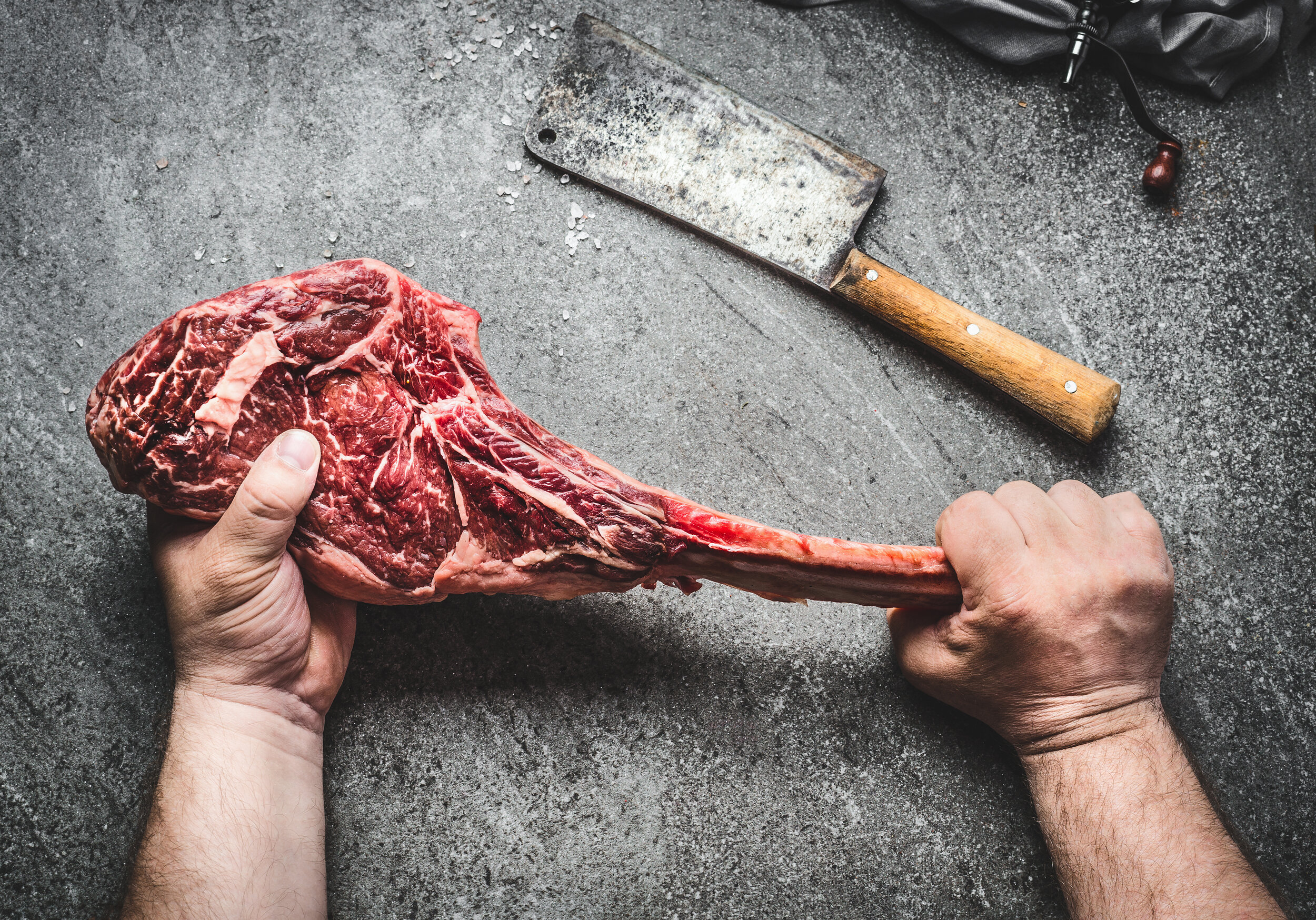 Butcher-hands-holding-tomahawk-steak-890775278_5299x3705.jpeg