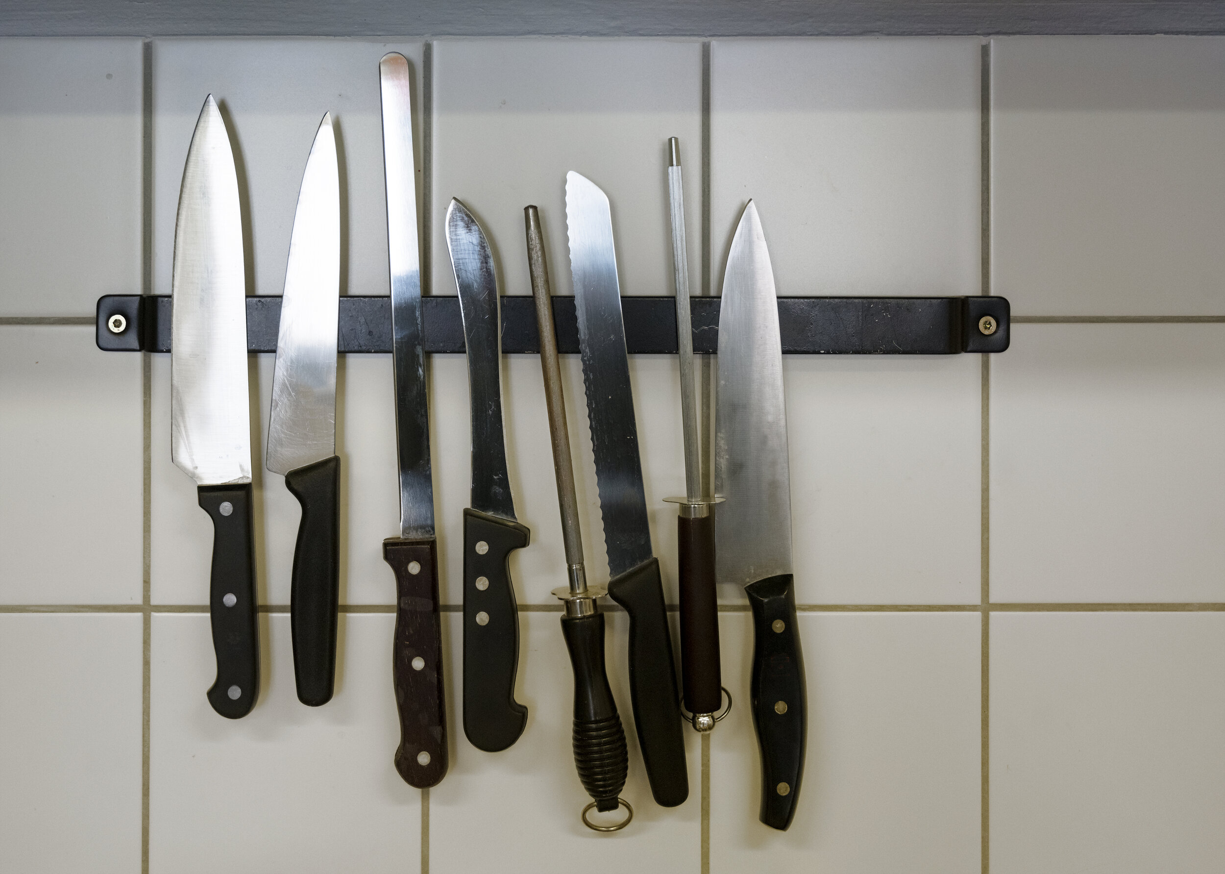 large-kitchen-knives-and-honing-steels-hanging-on-a-magnetic-holder-on-the-tiled-wall,-copy-space-1150455766_4500x3209.jpeg