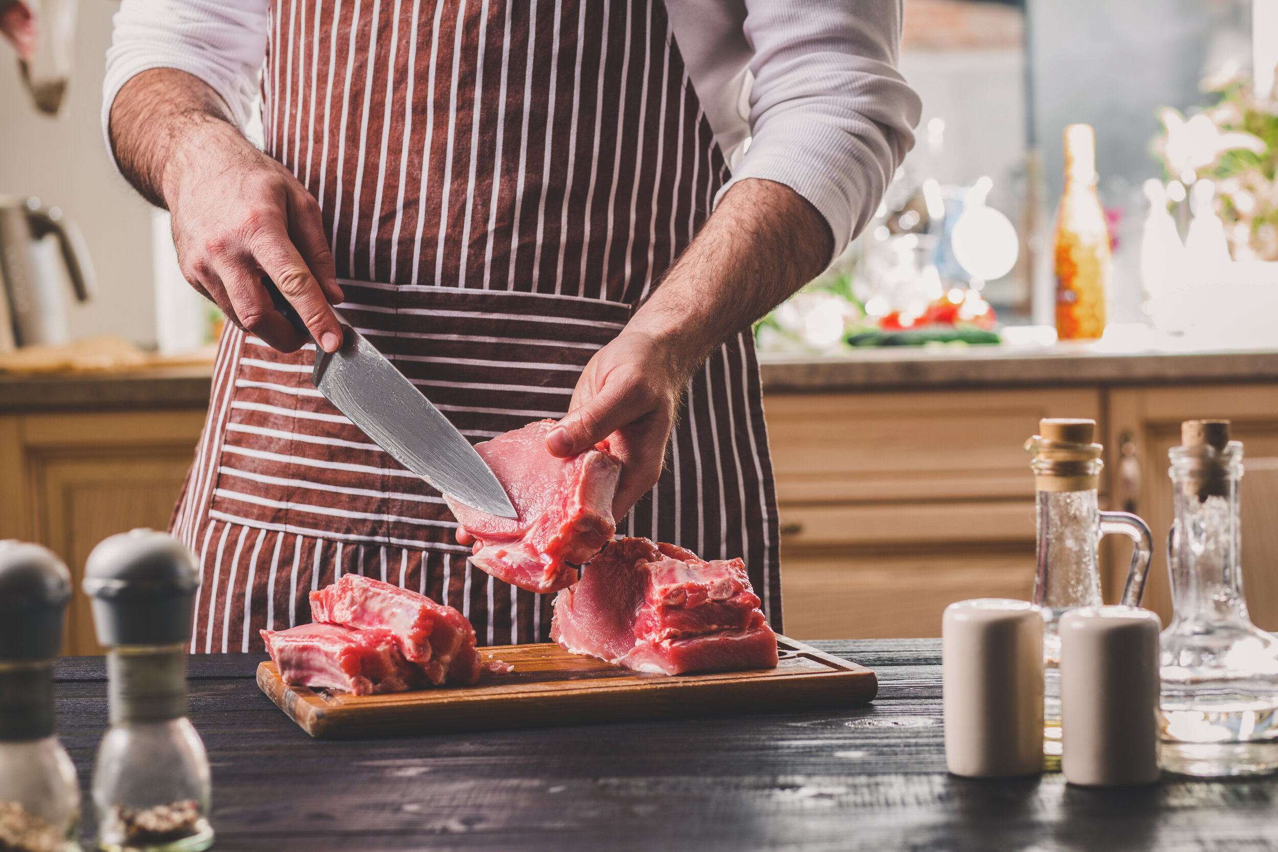 Man-cuts-of-fresh-piece-of-meat-on-a-wooden-cutting-board-in-the-home-kitchen-683987742_5760x3840.jpeg