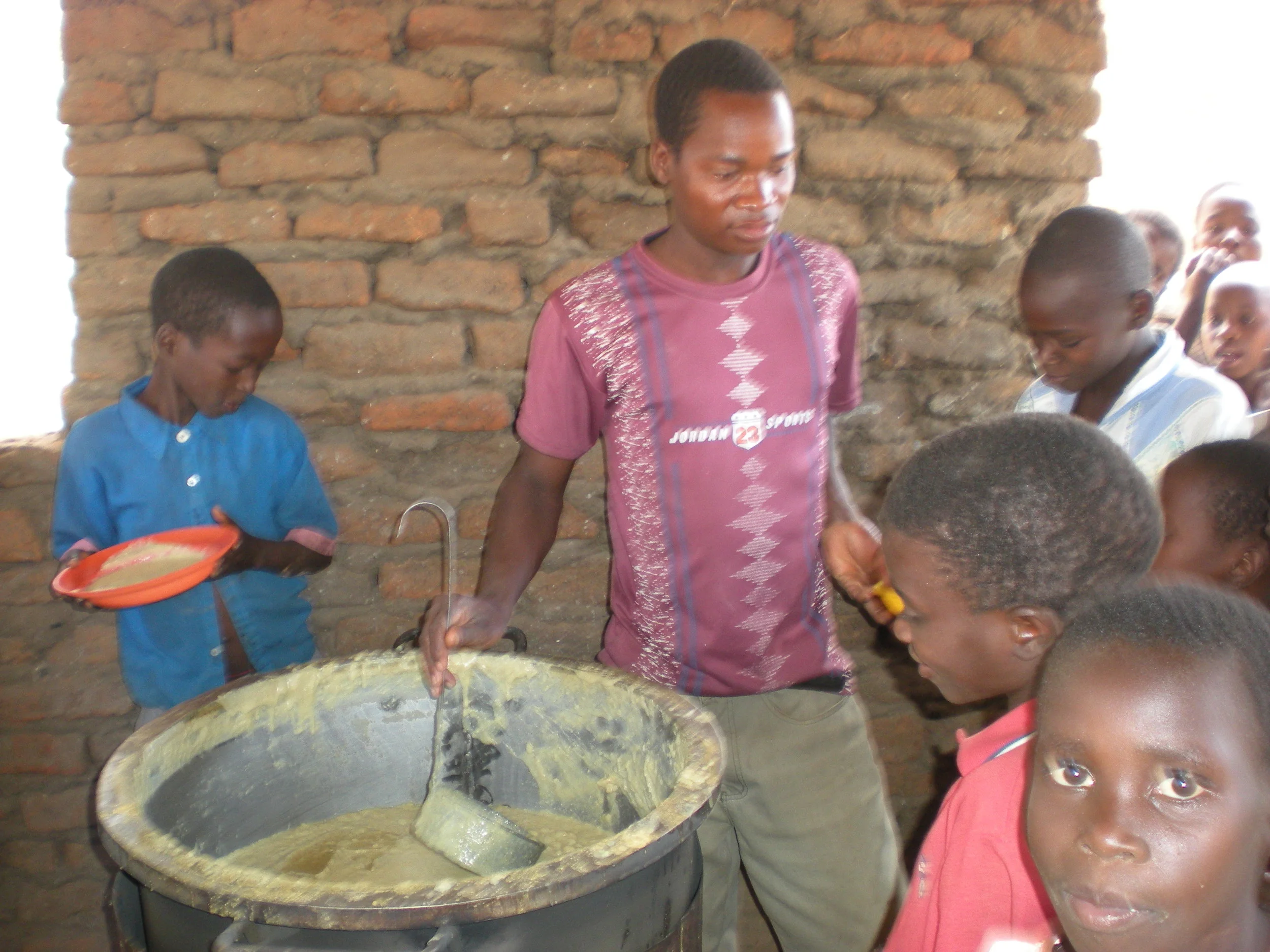 The photograph shows the chairman of the PTA at Napache School serving the porridge.