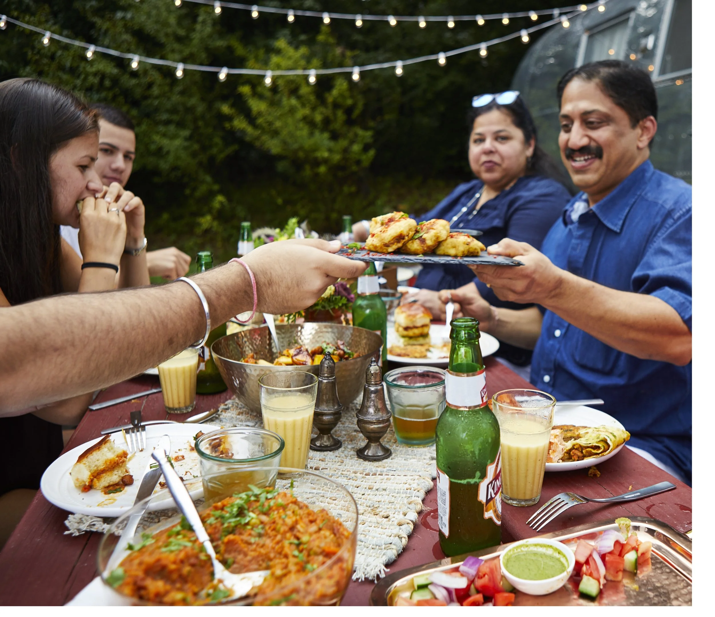 The Sunderam family gathers over a Indian-style casual meal. In the background, a 1964 Airstream named Lucy.