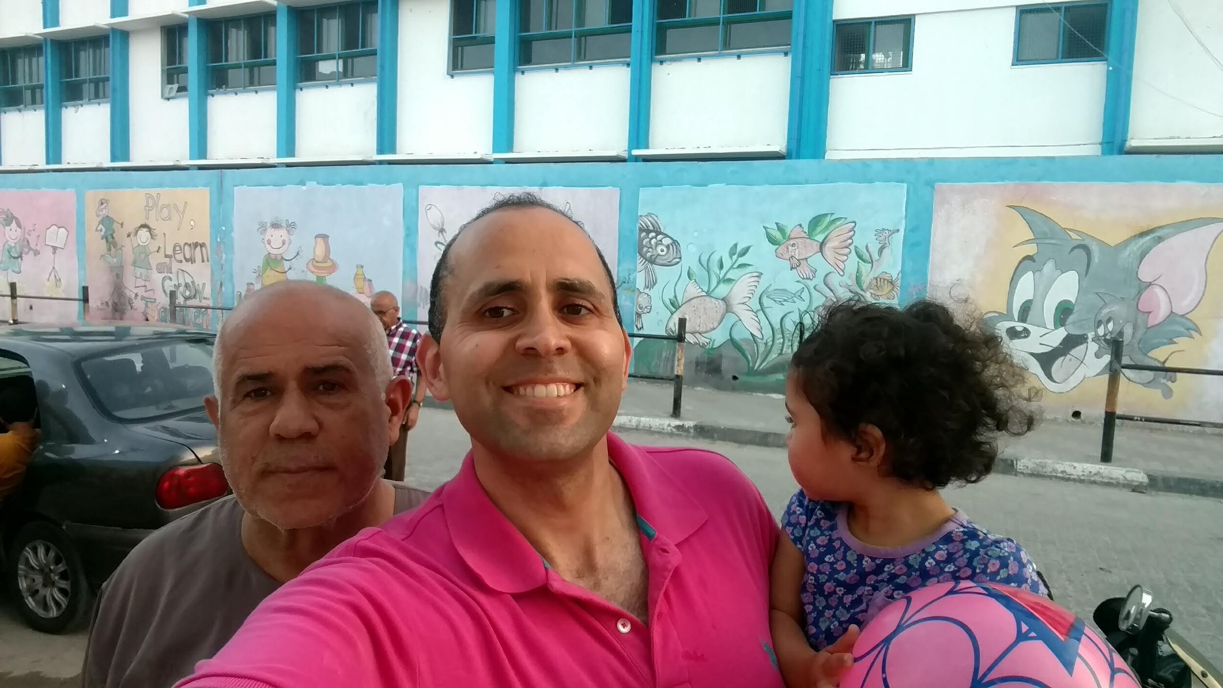 Hani and his uncle and daughter in front of an UNRWA school in the Gaza Strip