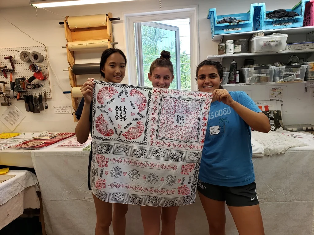 Students hold up work they created for Traditional Sanganeri Block Printing with Shanti Jain