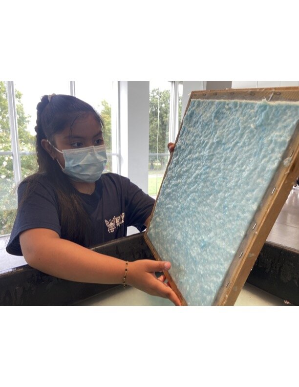 Workshop participant holding up blue, wet pulp on mould