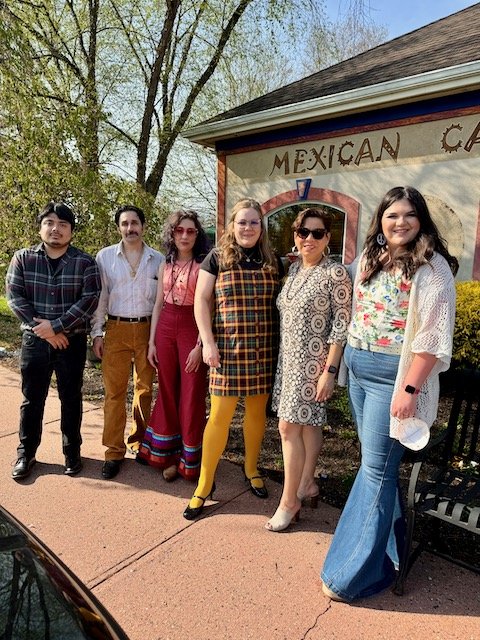  Hugo Gatica, James Teichman, Rachel Heberling, Kath Yarkosky, Gianna Seaman, and Lindsey Knipe all stand in line outside the restaurant on a clear day as they pose for a staff photograph. 