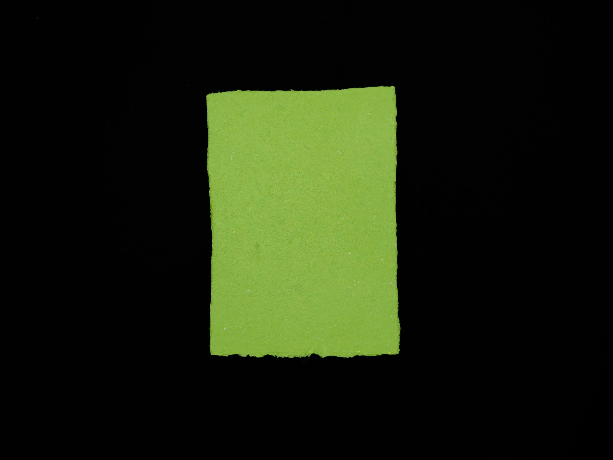 Kelly green sheet of handmade paper on a black background.