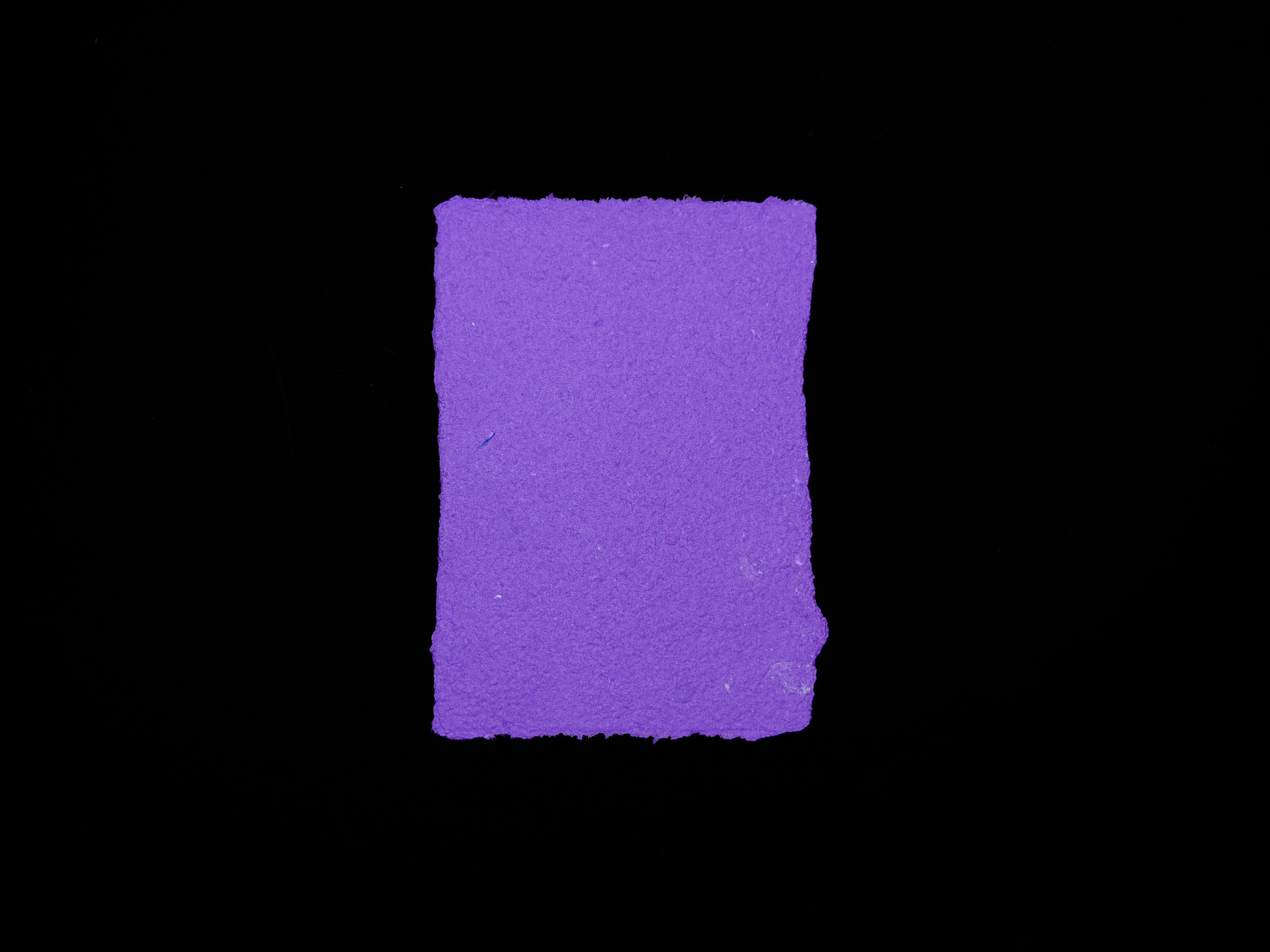 Deep purple sheet of handmade paper on a black background.