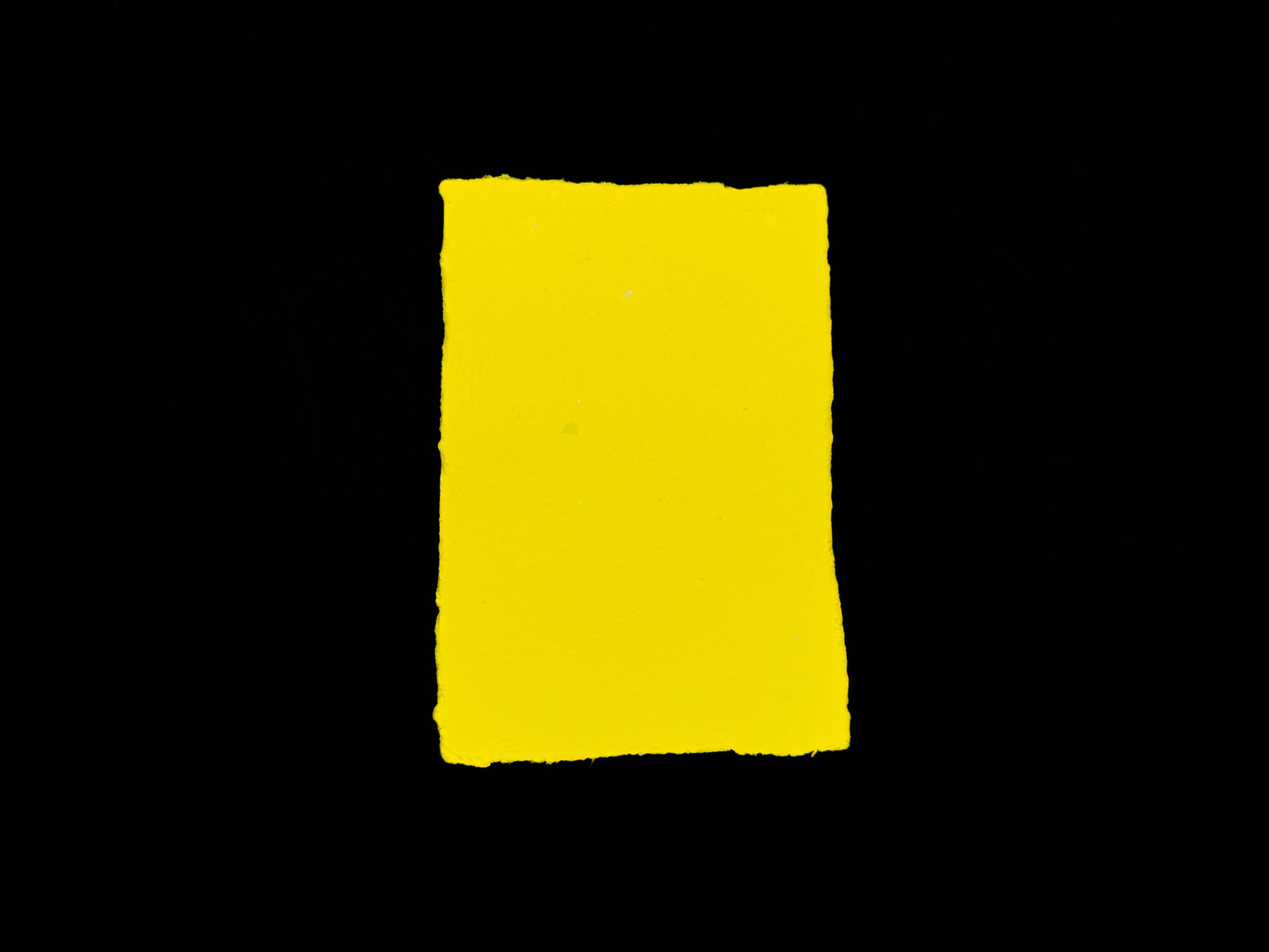 Yellow sheet of handmade paper on a black background.