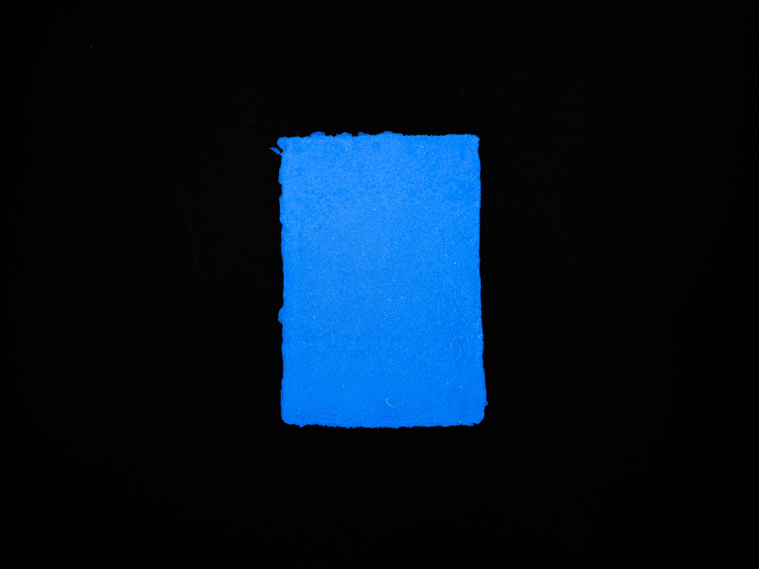 Royal blue sheet of handmade paper on a black background.