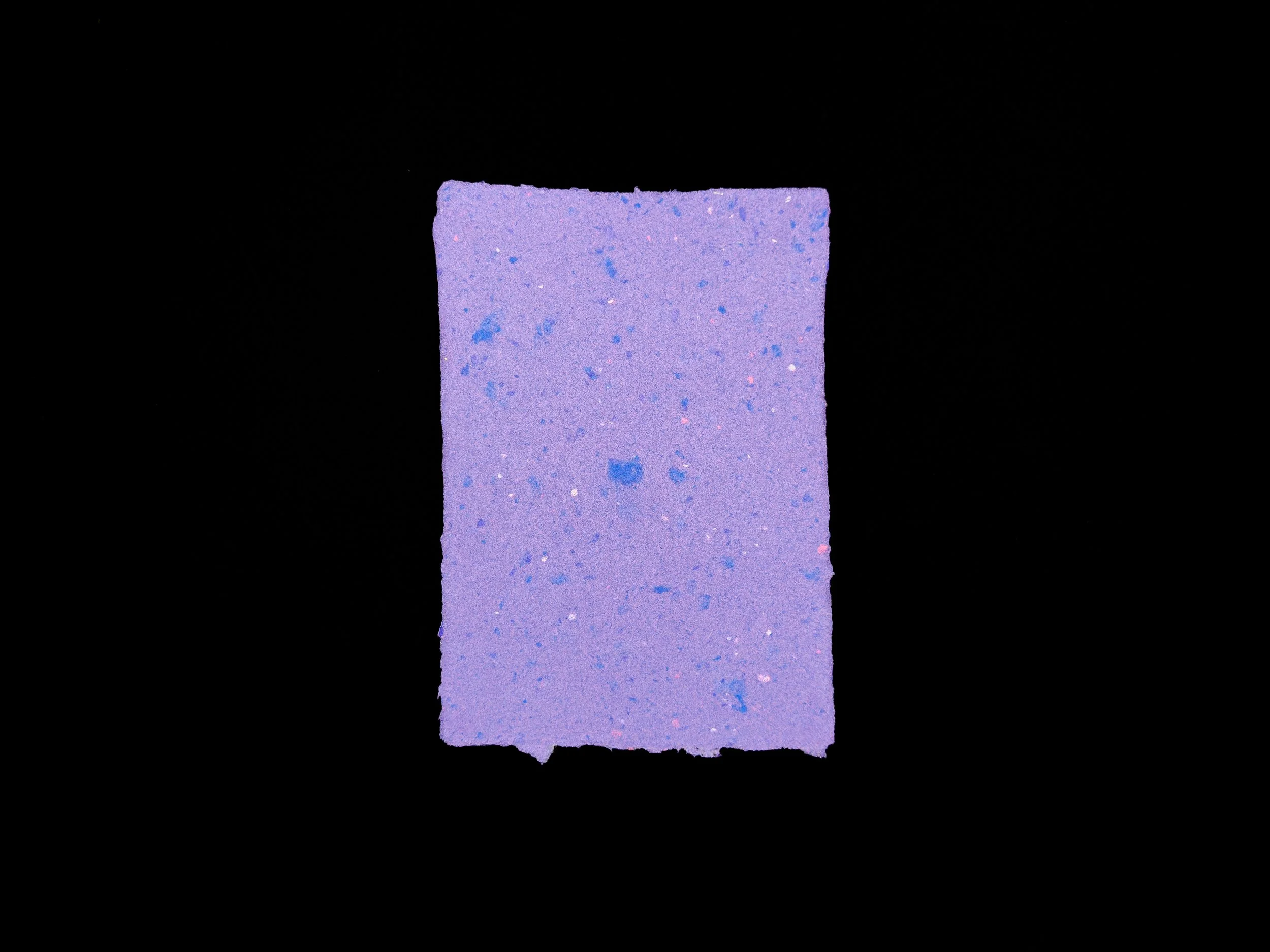 Dusty purple sheet of handmade paper on a black background.