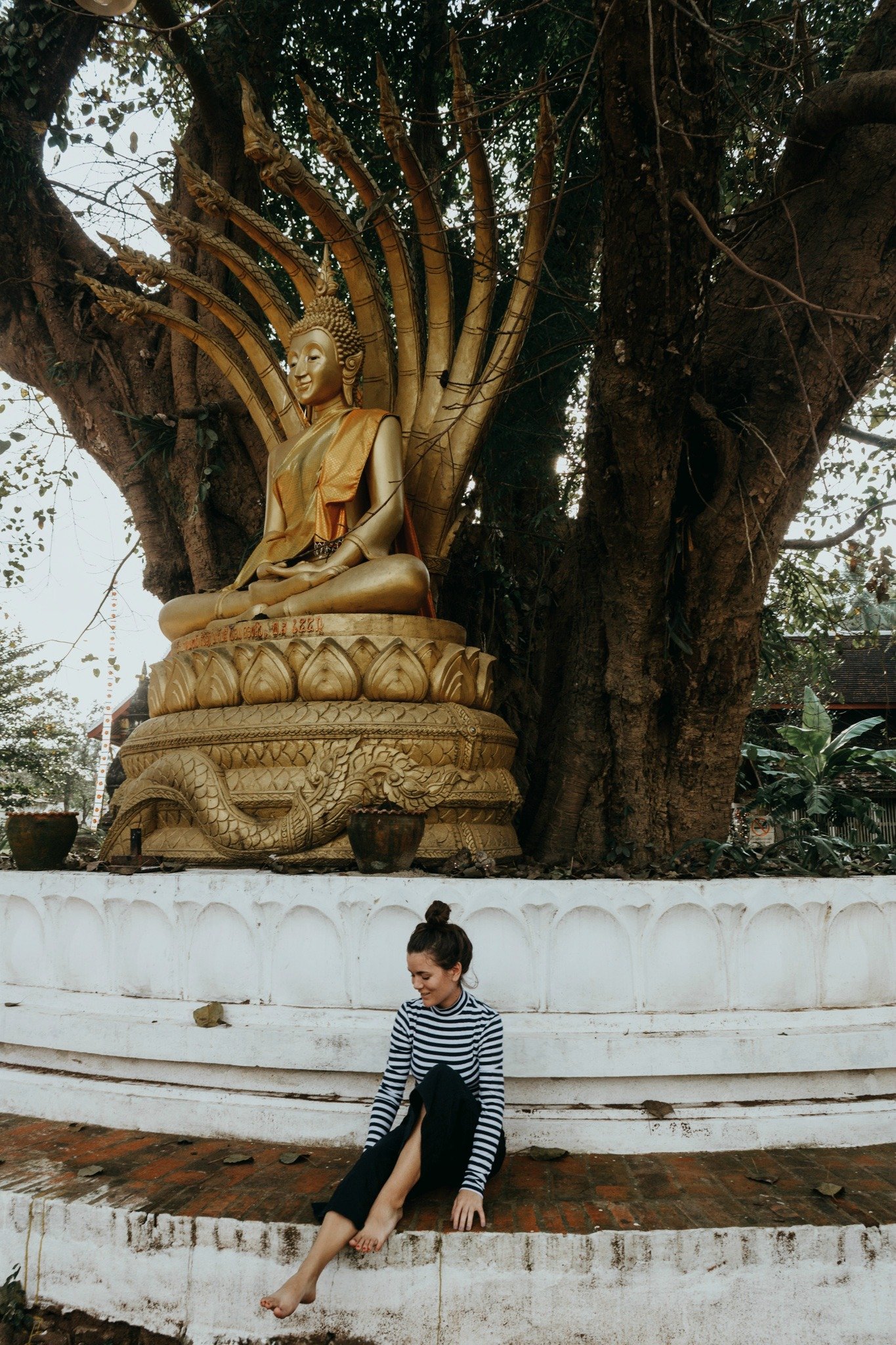 sitting underneath Buddha in Luang Prabang