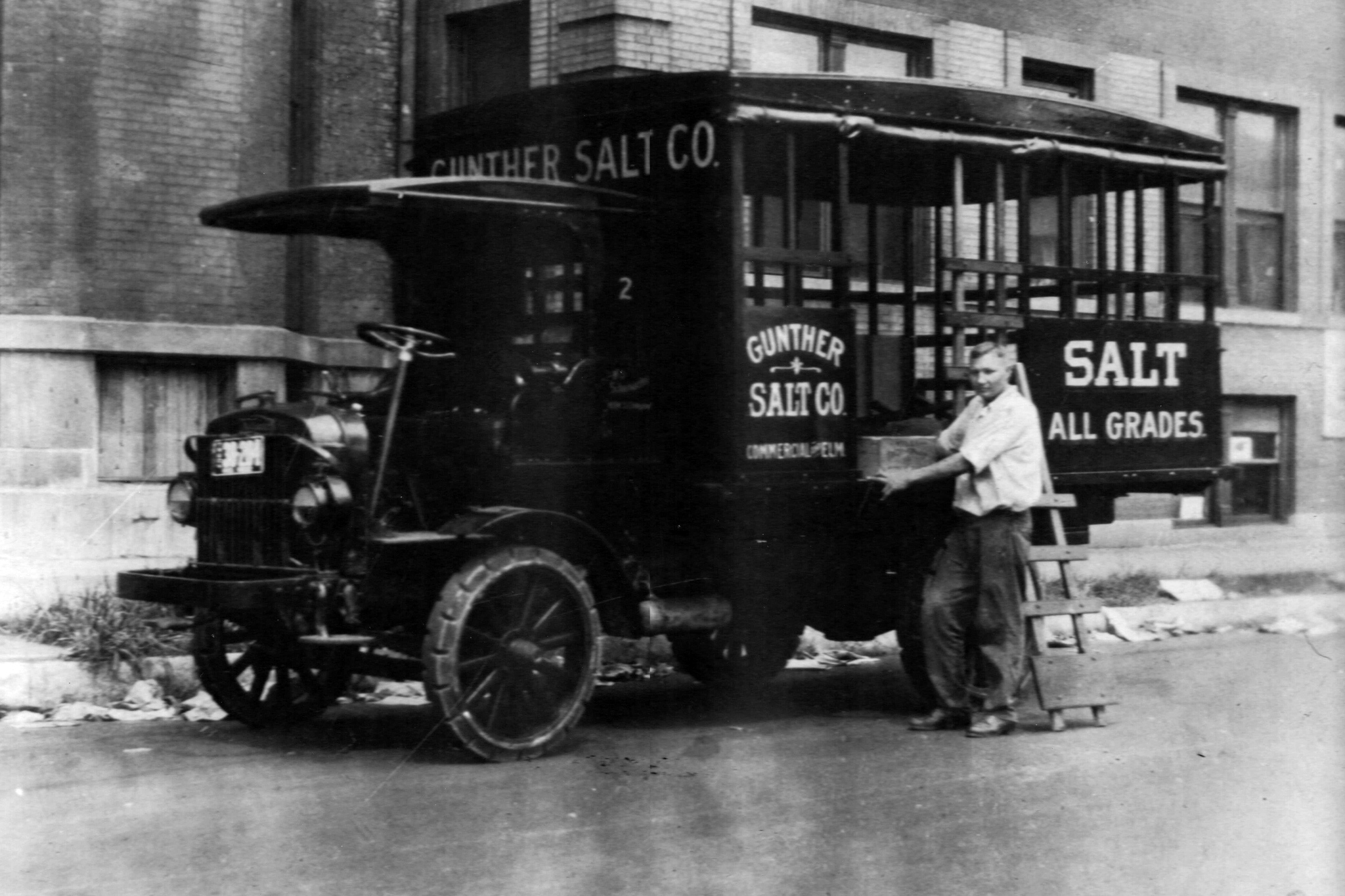 An employee of Gunther Salt Company is either loading or unloading the Gunther Salt Company truck to make his salt delivery. This photo has a date of August 15, 1922.