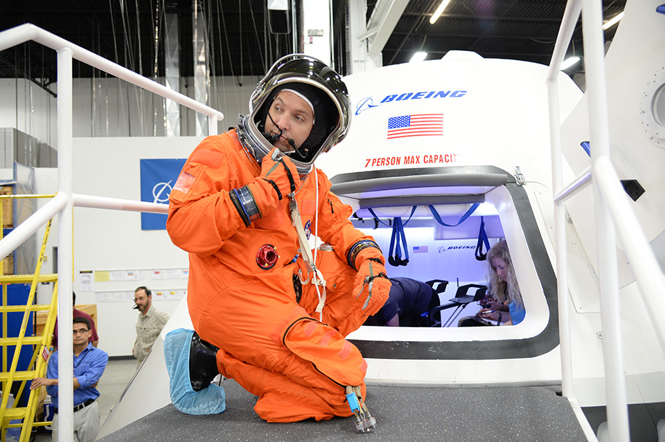  An astronaut practices entering the spacecraft in a flight suit. Photo Credit: Boeing 