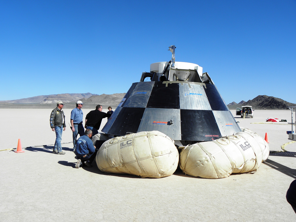 Engineers inspect a drop-test capsule. The test was to validate the airbag landing system. Photo Credit: Boeing