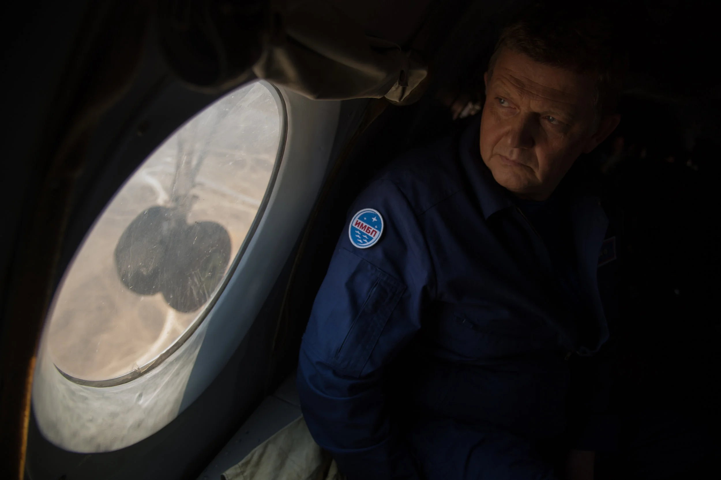 Director of the Russian Institute for Biomedical Problems (IMBP) Oleg Orlov looks out the window of an AN-26 aircraft as support teams pre-position to Zhezkazgan, Kazakhstan. Photo and Caption Credit: Bill Ingalls / NASA