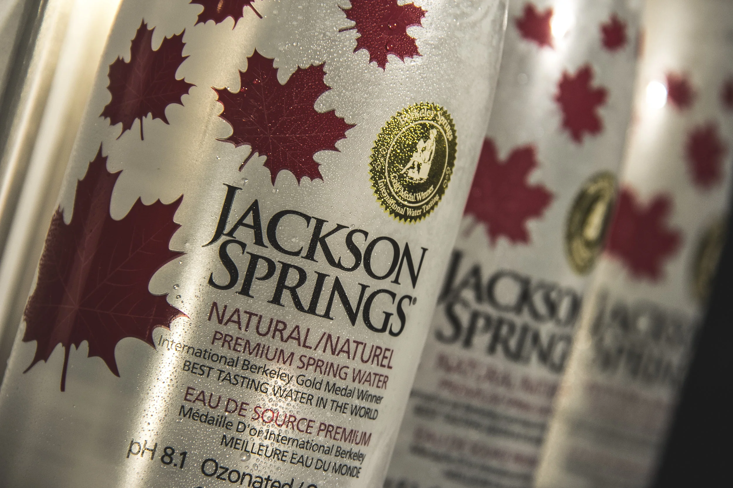 Close-up of Jackson Springs bottled water label featuring red maple leaves and gold medallion emblem.