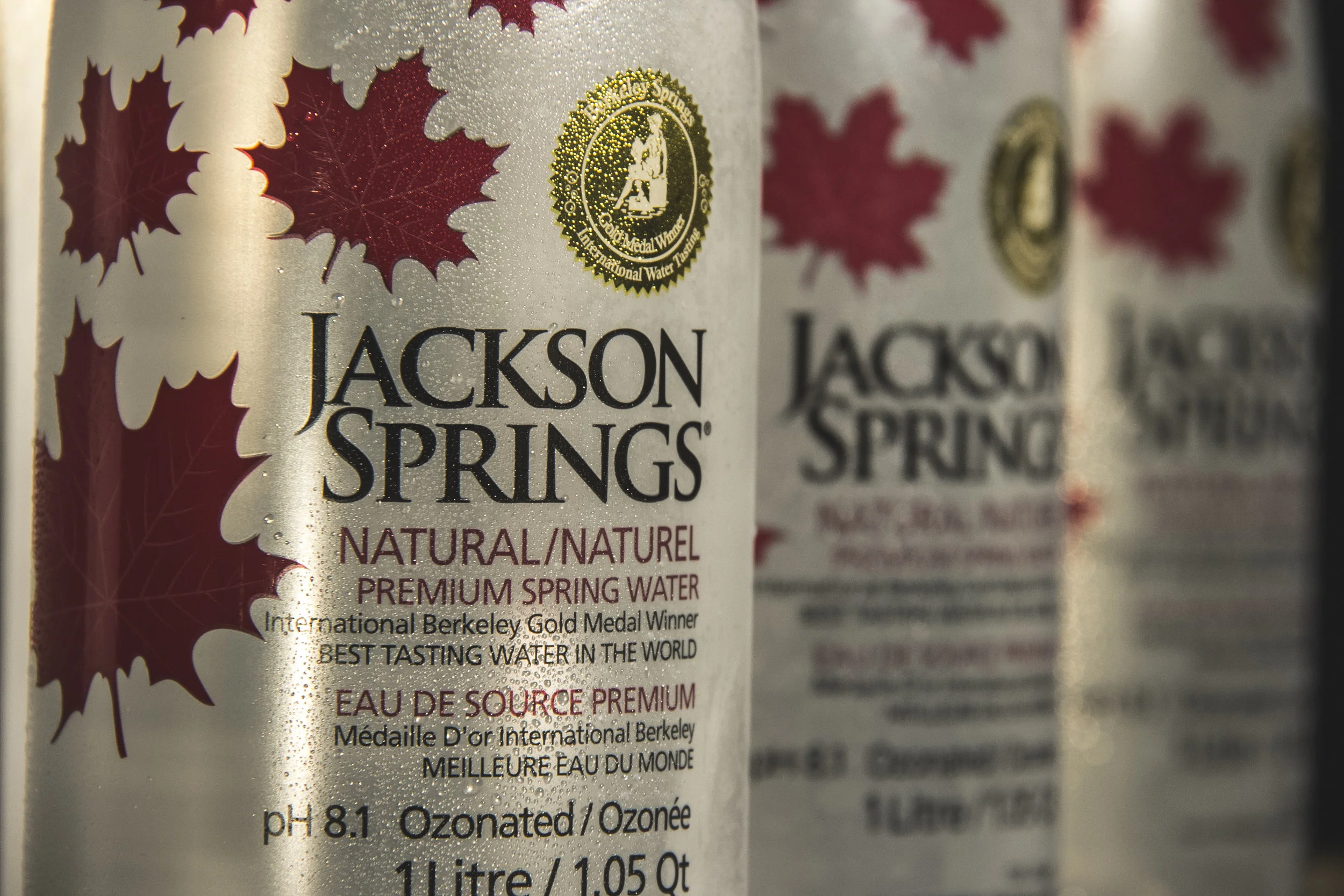 Close-up of Jackson Springs natural spring water bottles with red maple leaf designs.