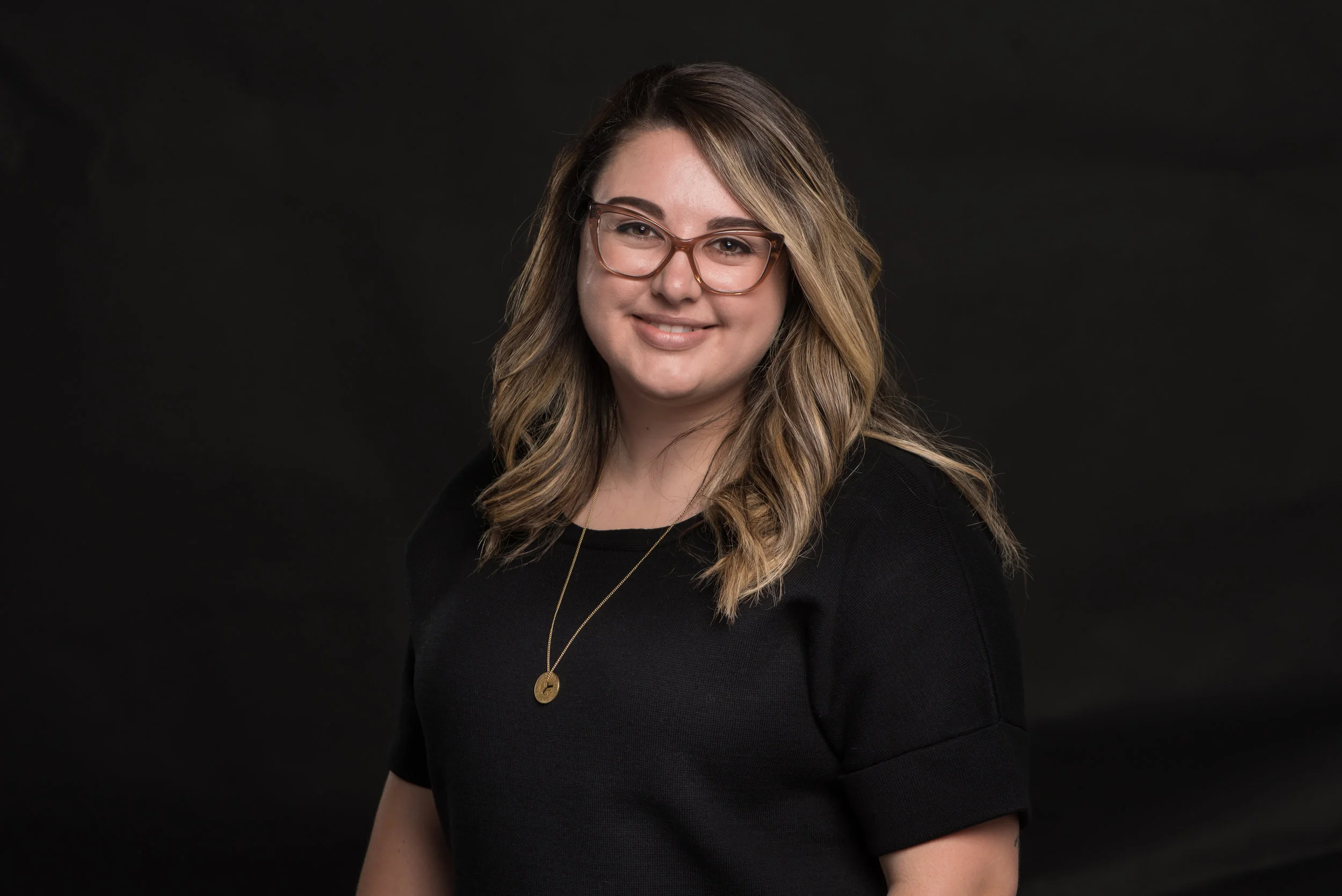 Headshot on a black backdrop of a female professional
