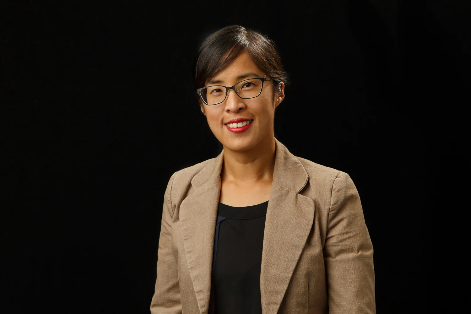headshot of an asian woman on a black backdrop