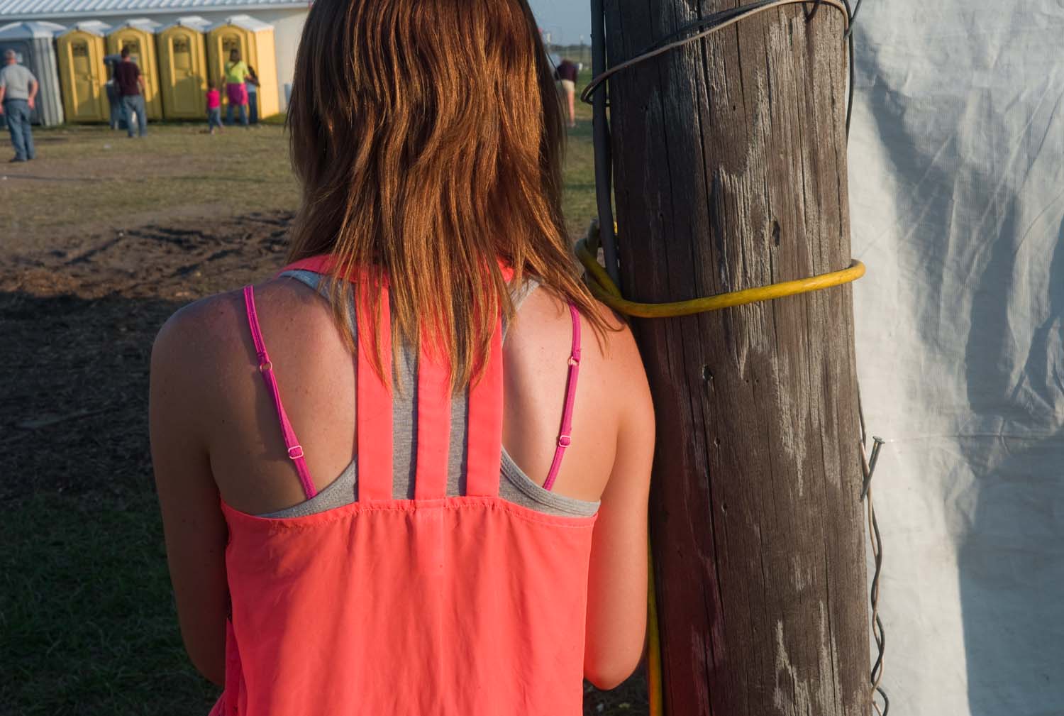  Red haired young woman wearing bright pink tank top looking at her phone at the Adams County Fair. Mendon, IL. July, 2014 