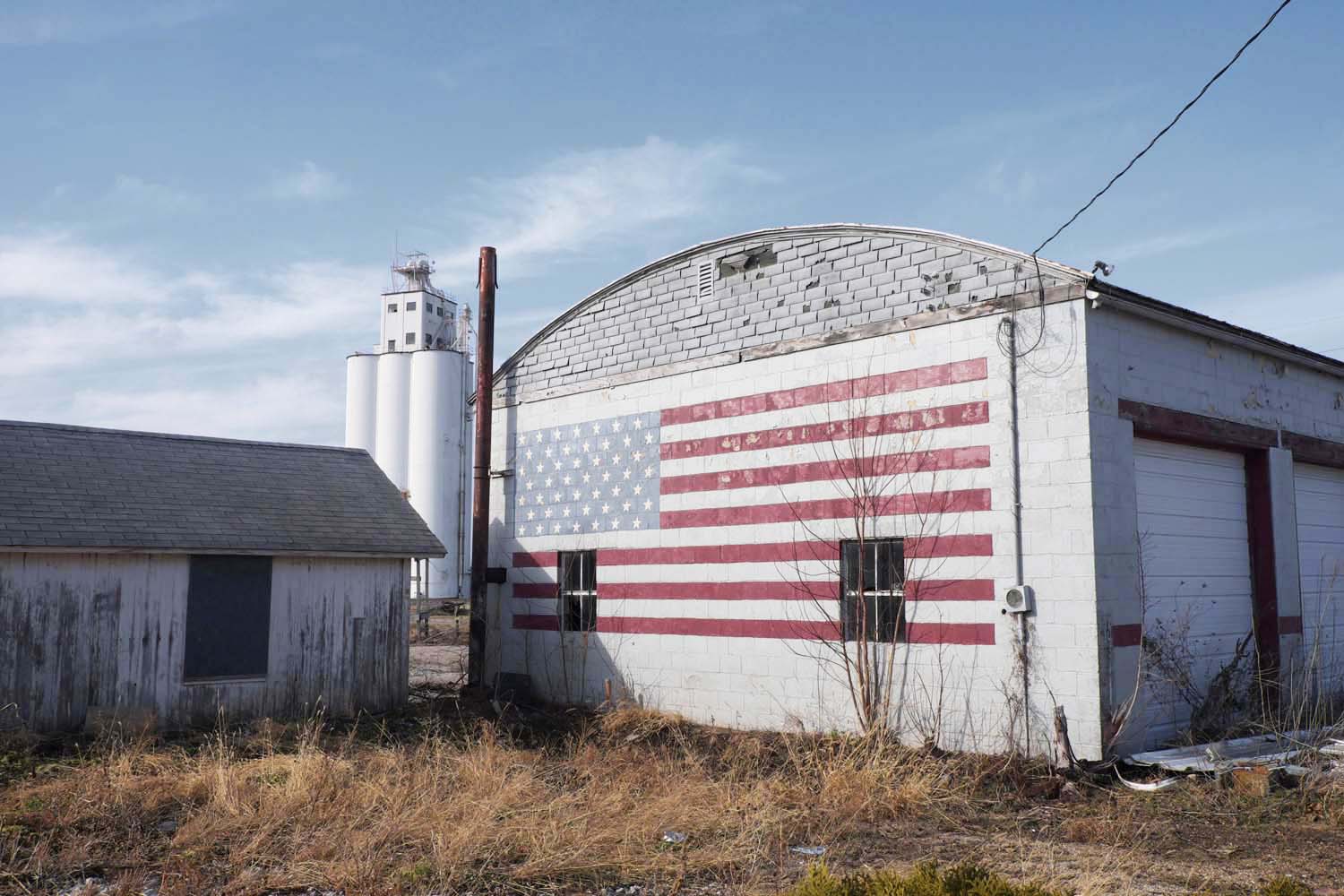  American flag on former gas station, grain elevator in background. Smithshire, IL. January, 2017 