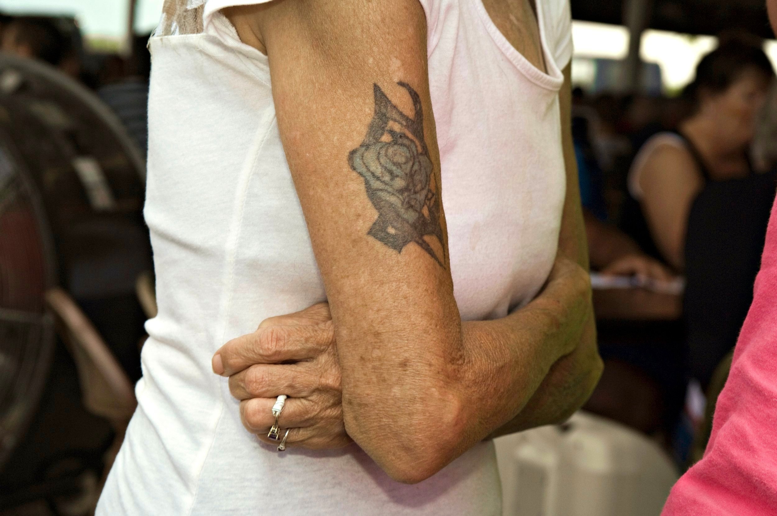  Older woman with arms crossed. On one arm is a rose tattoo. Hancock County Fair,  Augusta, IL. June, 2014 