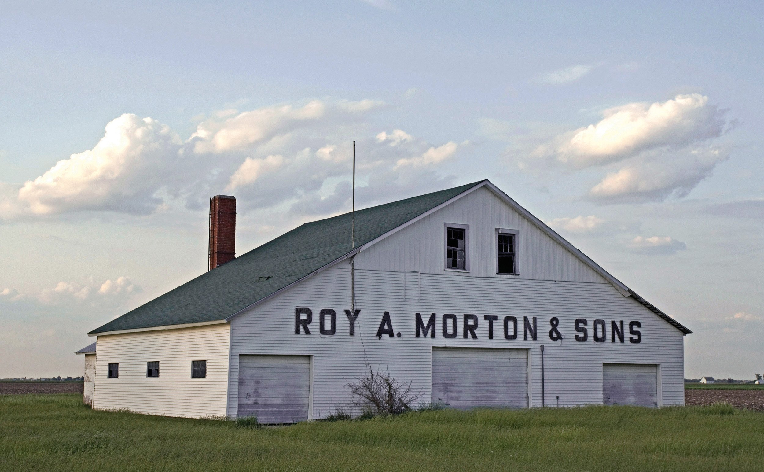  Roy A. Morton &amp; Sons is Bruce’s granfather’s drying barn. In this barn ears of corn would be loaded through the top two windows and dropped into bins. A furnace in the back would blow hot air on the corn to dry. The furnace ran on coal and then 