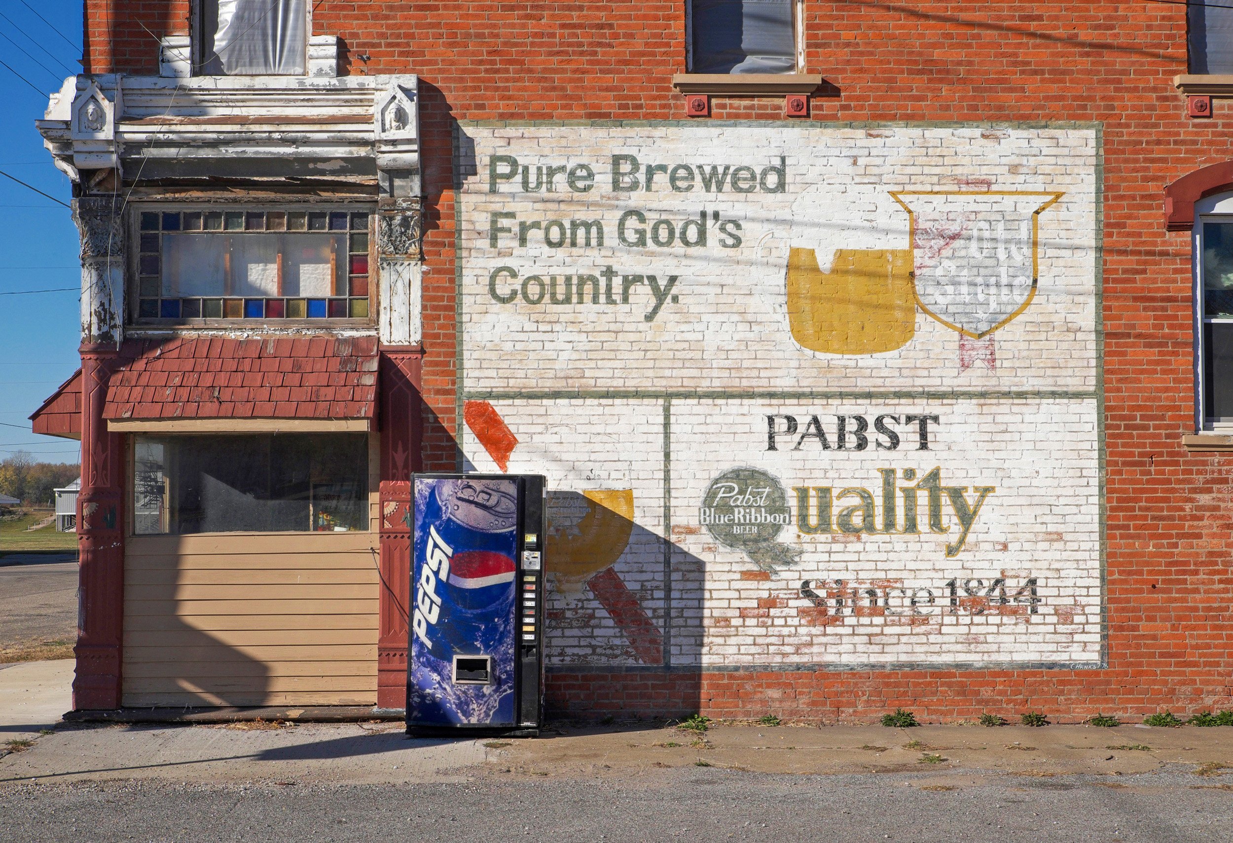  Painted ads on brick building reads “Pure Brewed from God’s Country” Old Style Beer, Pabst Blue Ribbon beer since 1844. Pepsi vending machine in front. Oquawka, IL. November, 2016 