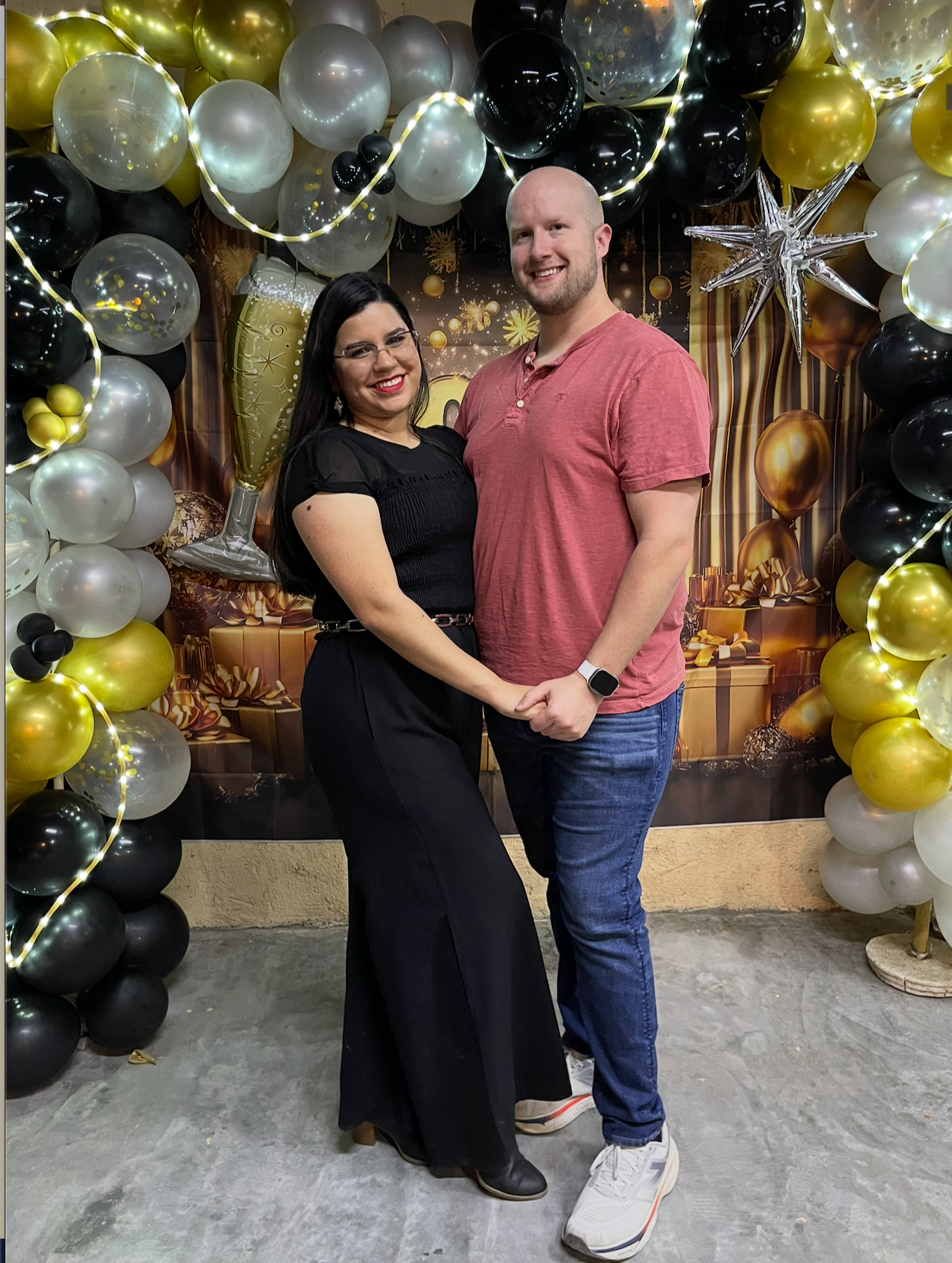 A woman and man posing for a picture infront of New Years decorations,