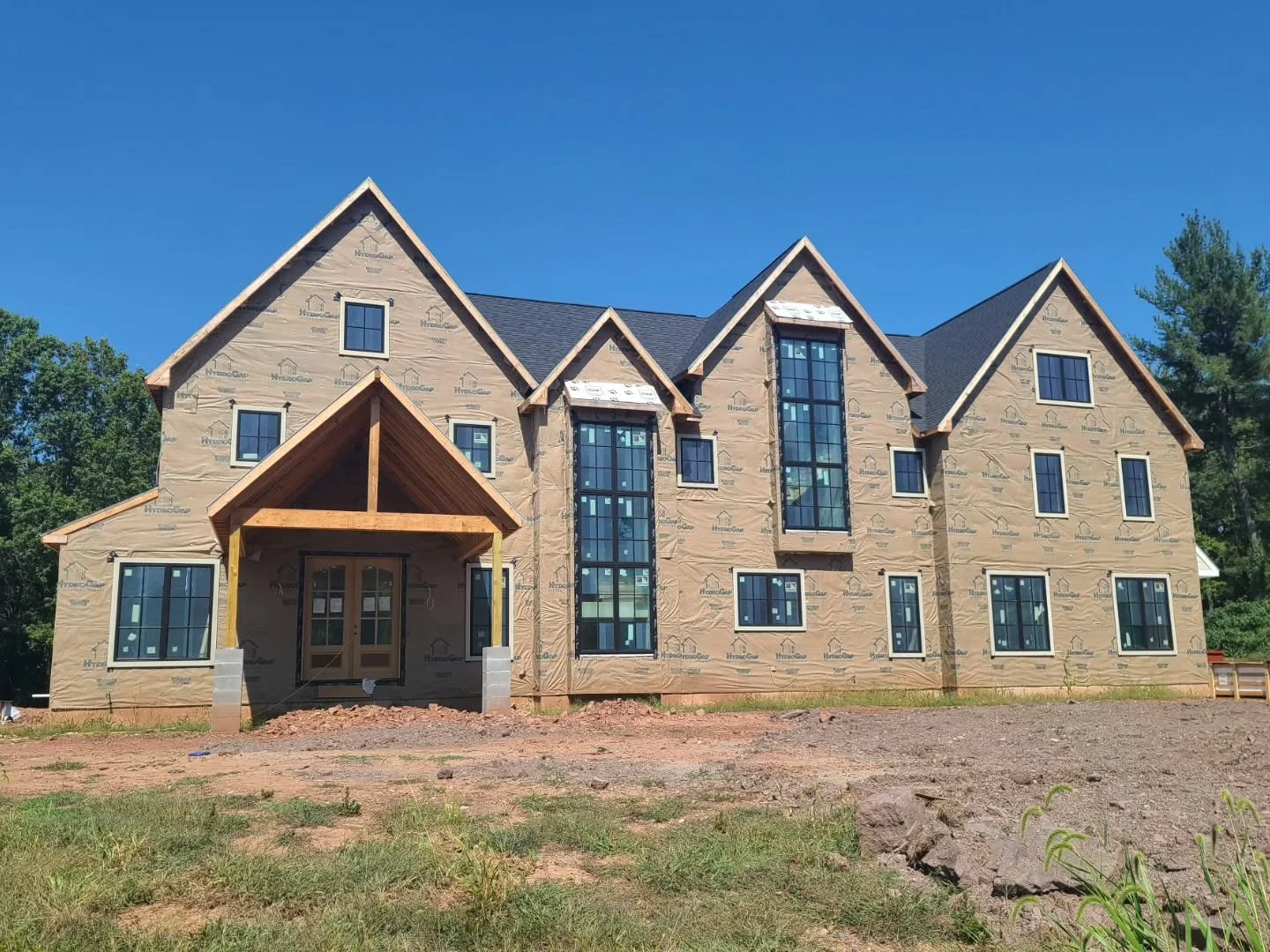 With the front porch framed, our Collegeville custom home is starting to reveal itself. The prominent vertical windows highlight not one but two staircases. At the rear, similar windows will flood the great room with an abundance of natural light.

W