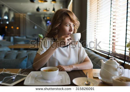 stock-photo-portrait-of-young-gorgeous-female-drinking-tea-while-looking-out-of-the-coffee-shop-window-and-315826091.jpg