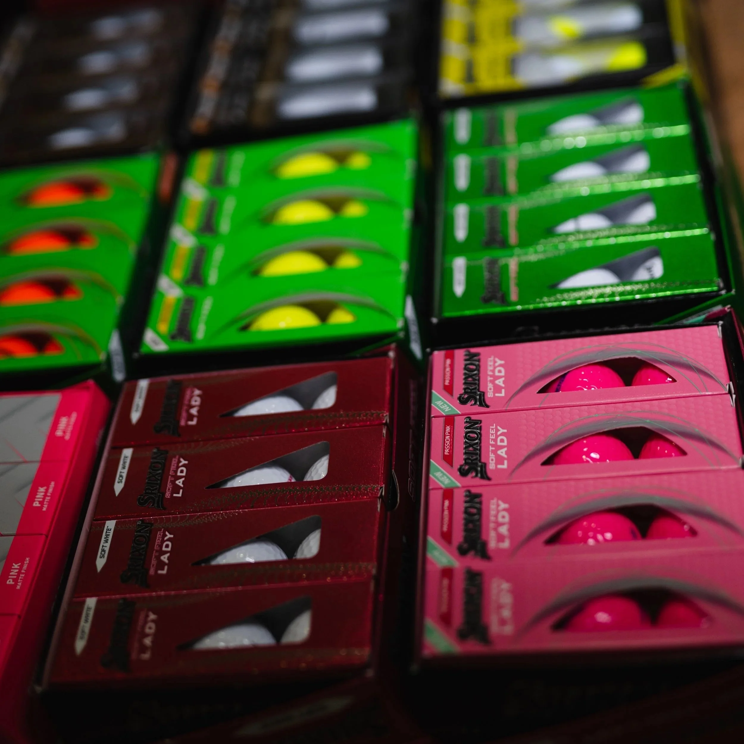 Multiple boxes of pink and green lipstick in a store display.