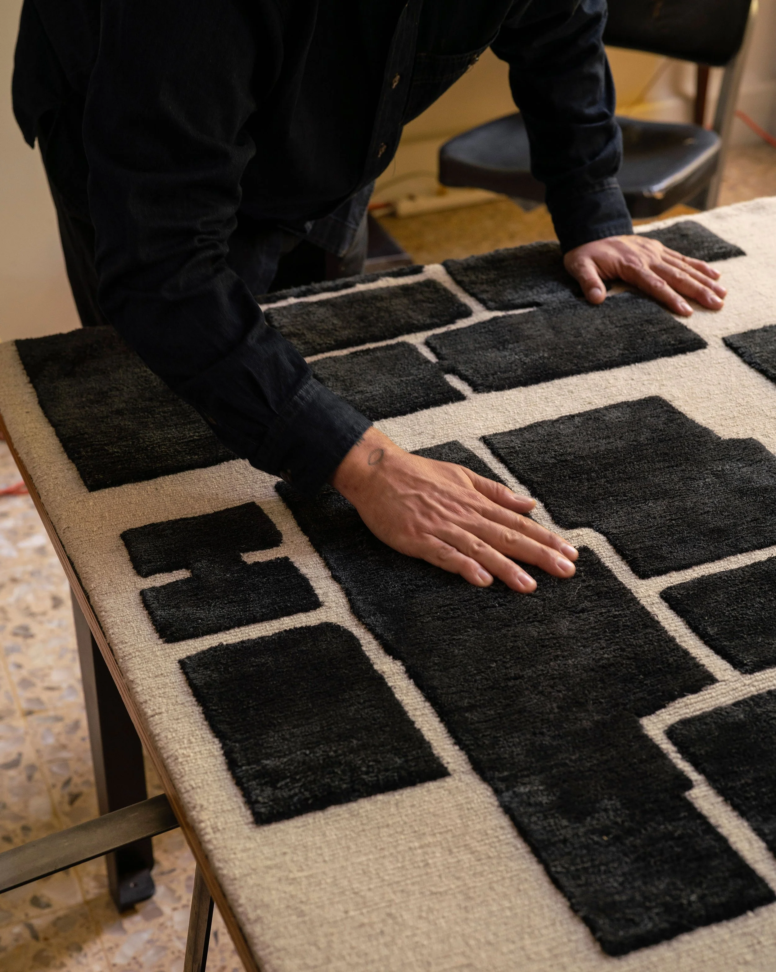 Lucas Cantú's hands as he touches and examines the Laberintos 02 low design rug created for exclusively for Radnor.