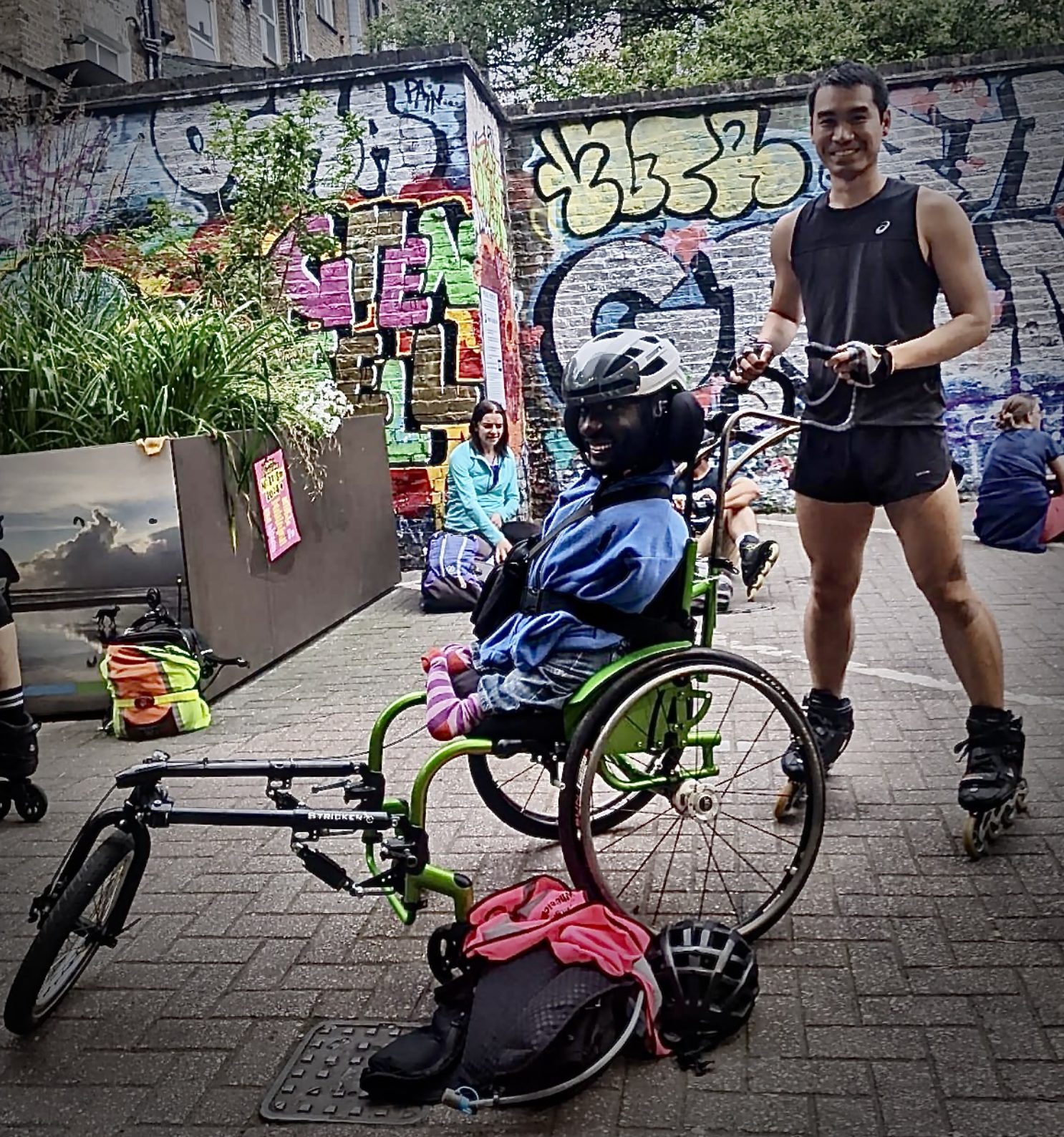 Wheelchair user Isaac Harvey and rollerblader Kevin Ly  on a Wheels and Wheelchairs skate enjoying accessible sport
