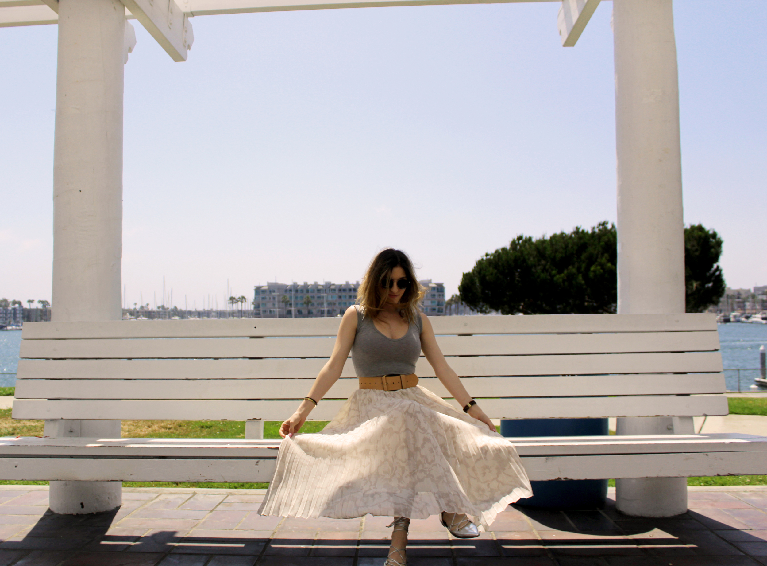 Top: Boohoo // Skirt: Banana Republic // Belt: Banana Republic // Shoes: Banana Republic, similar here // Sunnies: Le Specs The piece that I want to focus on in todays post is the pleated maxi skirt. I am pretty short so I never really thought a maxi skirt, especially a full one with pleats, would look good on me. This skirt from Banana Republic actually comes in petite, so that of course helped a lot as far as the fit went. But the skirt in general is absolutely beautiful, from the fit to the pattern and pleats, I love it all! I found that this type of skirt looks a lot better on me when I pair it with a wide belt like the one above. It pulls the look together and really brings out my waist line, which makes the skirt feel and look more feminine. Pleats are also a trend that has grown on me as I have gotten older. Adding the pleats with the floral design really make this skirt stand out for me and I love that about it. My brother and I actually went walking in the park this day along the water and ended up walking upon some of the best photo locations for this outfit! I'm in love with these cute little white benches and will definitely be bringing someone special back here for a picnic ( my dog of course!). Anyways thanks for stopping by and keep following for more new looks!!! Ciao!
