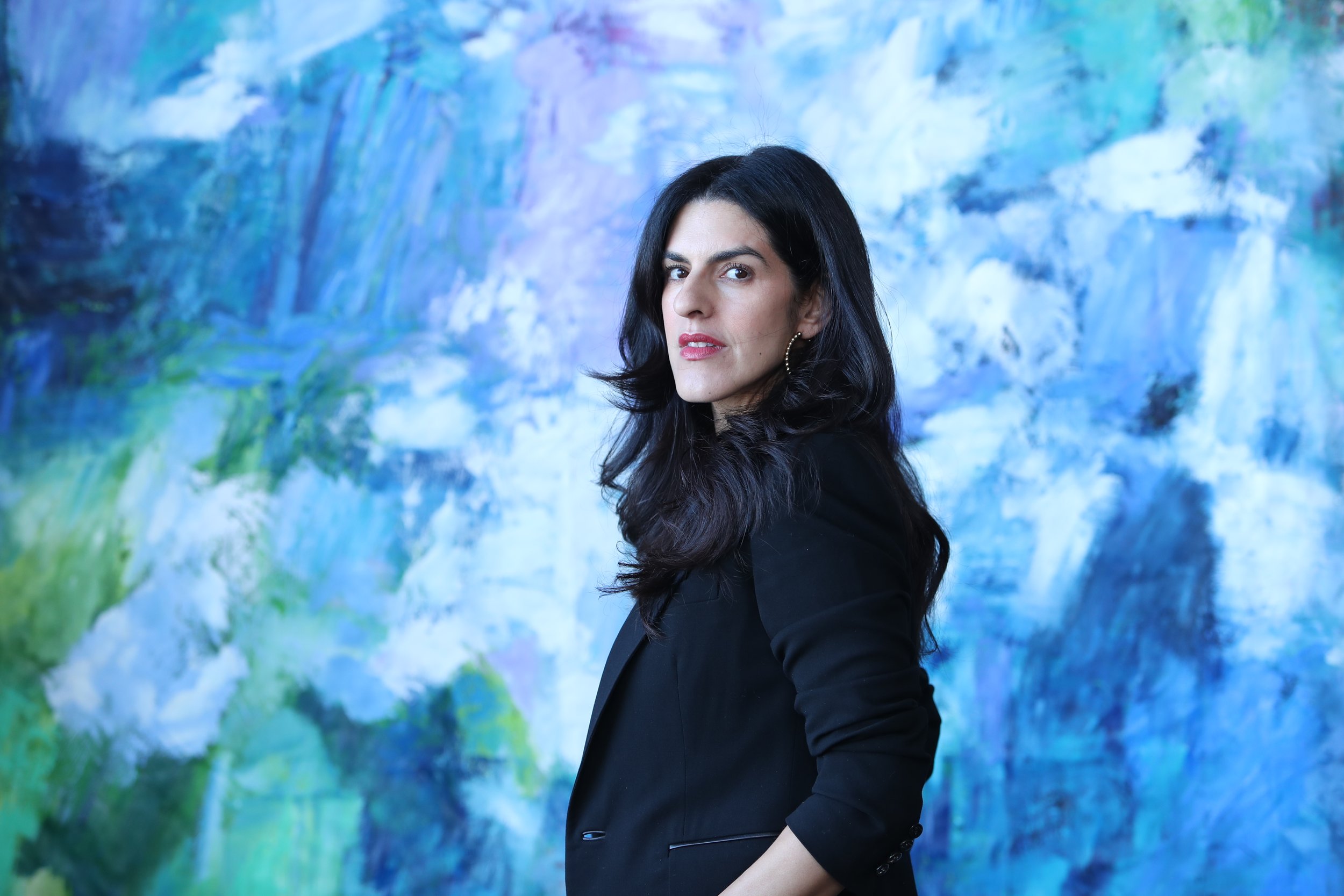 Contemporary artist Monica Shulman inside her studio in front of blue artwork commissioned painting in the Hudson Valley of New York.