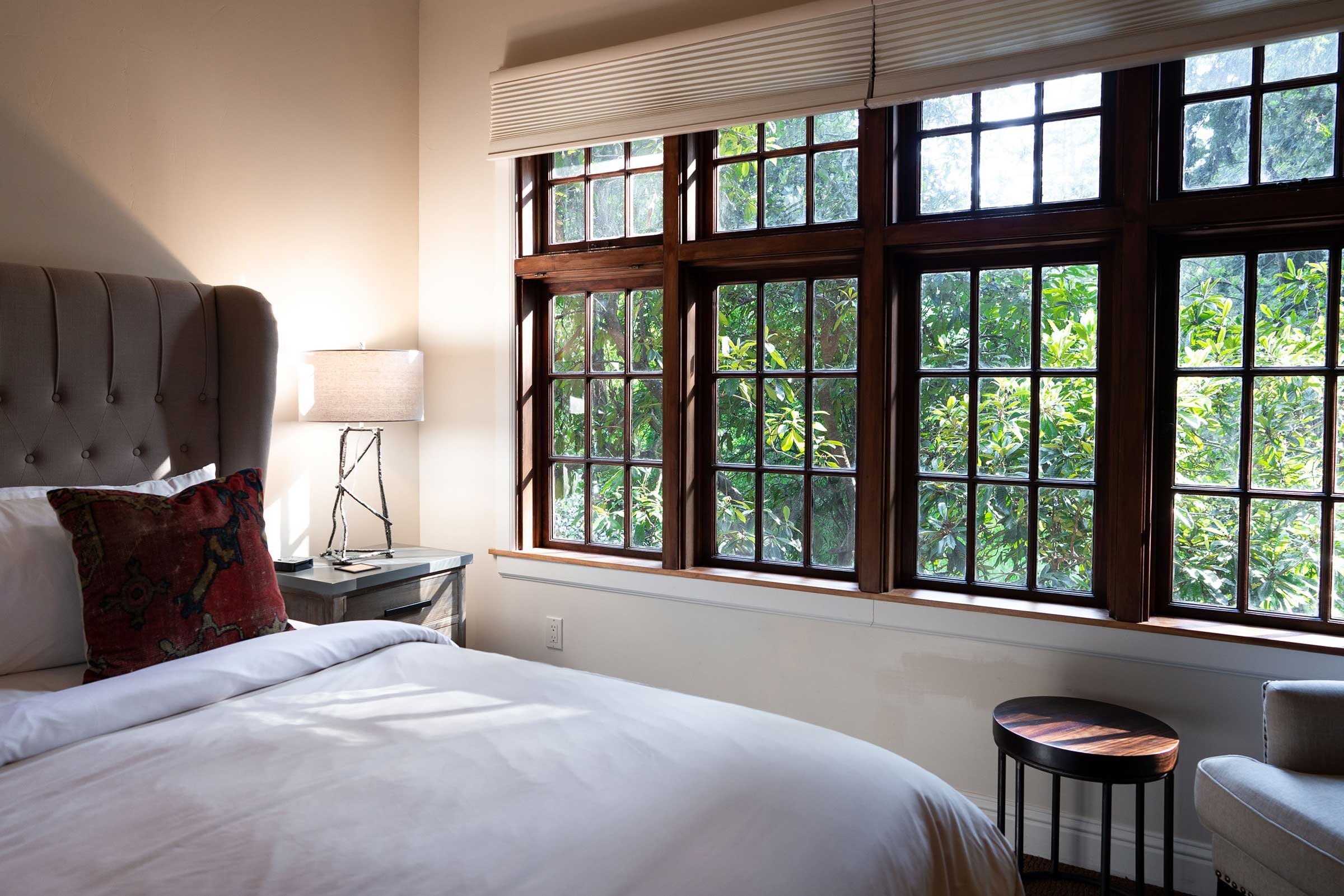 bed next to windows with a forest view at The Perch, Brambles Hideaway in Philo, Anderson Valley, CA