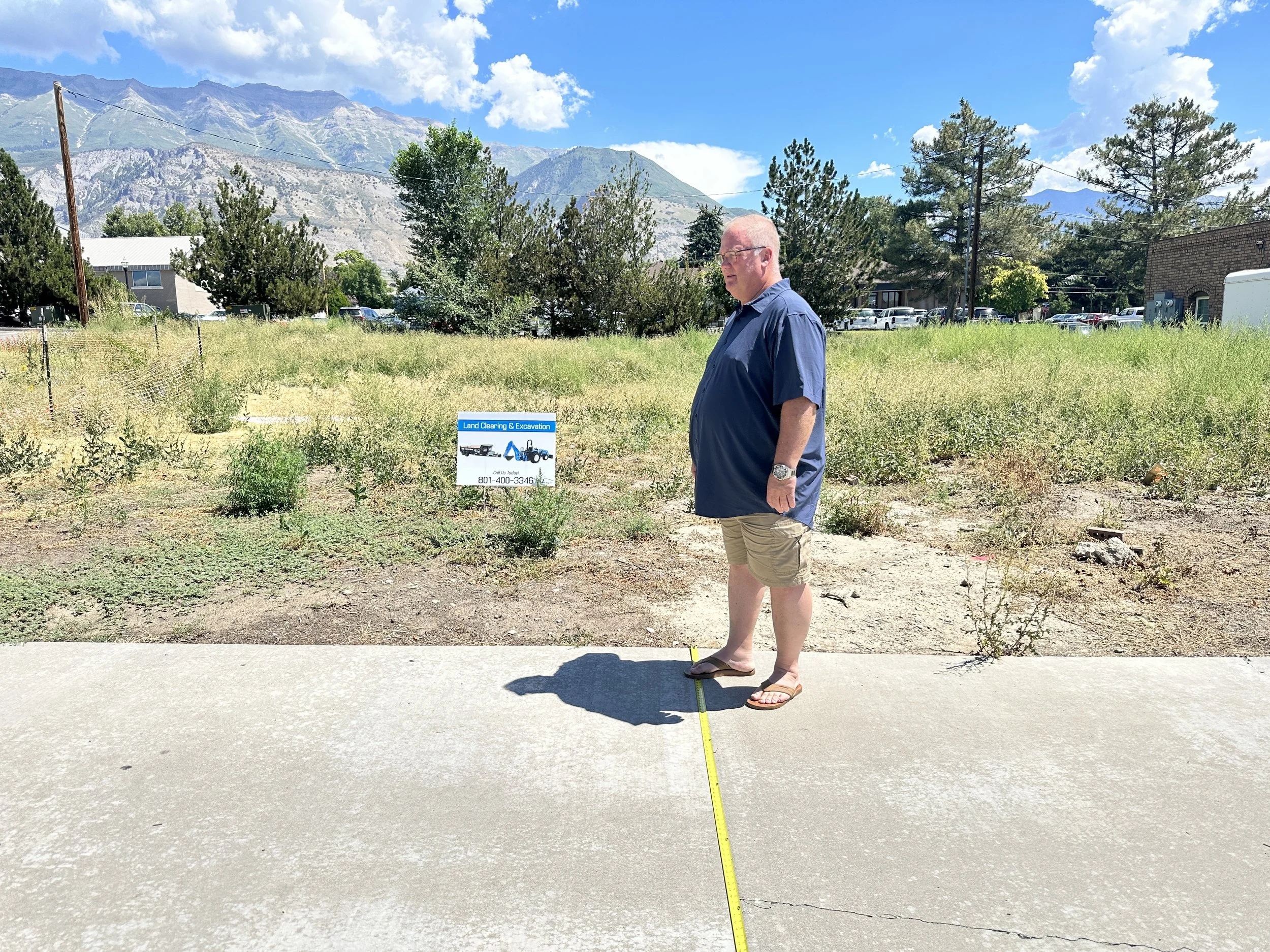 Brian holding the measuring tape on the east edge of the sidewalk.